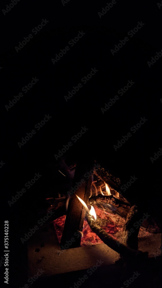Заголовок: Camp fire in the night. Bonfire. Flame and fire sparks on dark background. Black copy space.