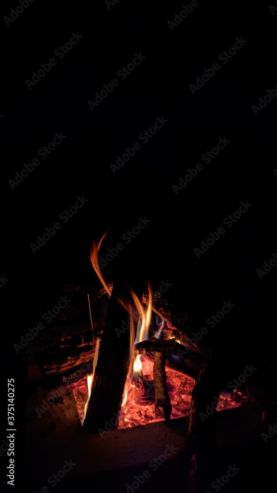 Заголовок: Camp fire in the night. Bonfire. Flame and fire sparks on dark background. Black copy space.