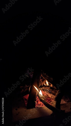Заголовок: Camp fire in the night. Bonfire. Flame and fire sparks on dark background. Black copy space.