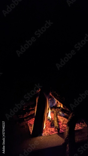 Заголовок: Camp fire in the night. Bonfire. Flame and fire sparks on dark background. Black copy space.   © Julia
