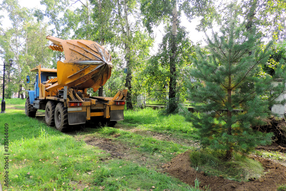 Obraz premium Tree transplanter heavy machine. machine for transplanting large trees. Planting large spruce trees in the park 