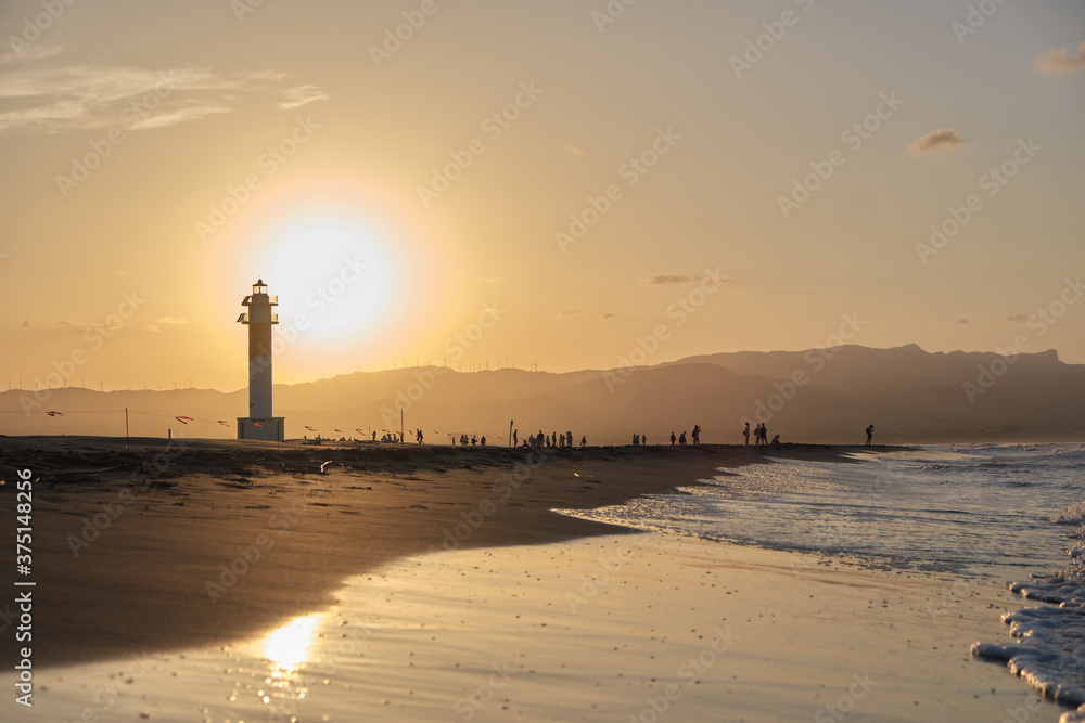 A group of people enjoy a beautiful golden sunset in a lighthouse