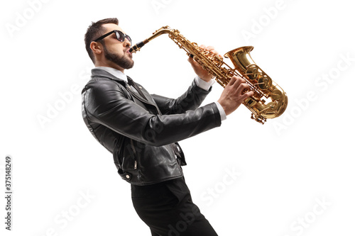 Side shot of male musician in a leather jacket playing a saxophone