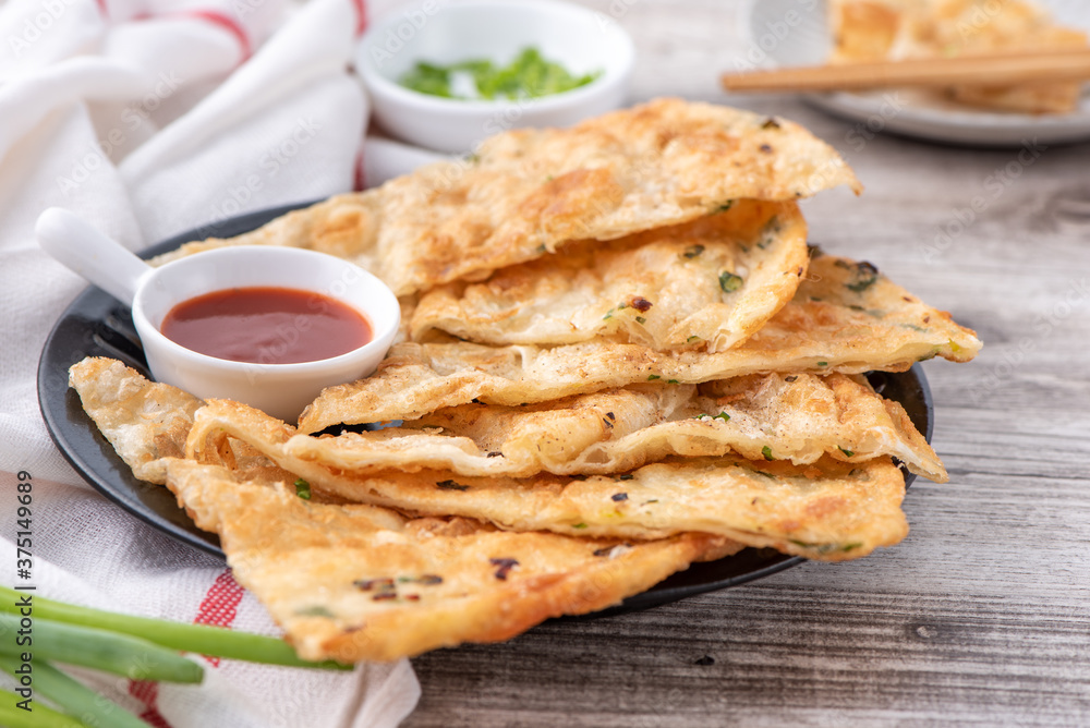 Taiwanese food - delicious flaky scallion pie pancakes on bright wooden table background, traditional snack in Taiwan, close up.