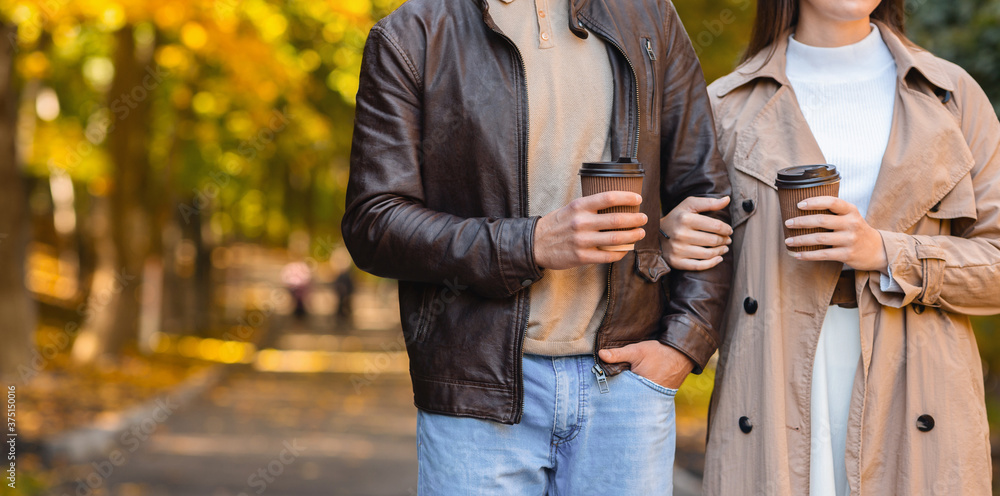 Cropped of man and woman drinking coffee while walking Cropped of man and woman drinking coffee while walking