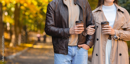 Cropped of man and woman drinking coffee while walking