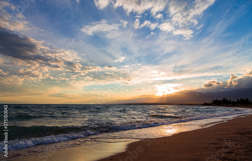 Beautiful sunset by the lake. Bright clouds are reflected in the water. Kyrgyzstan.