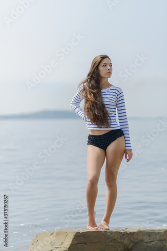 Woman in a striped T-shirt keeps near the breakwater.