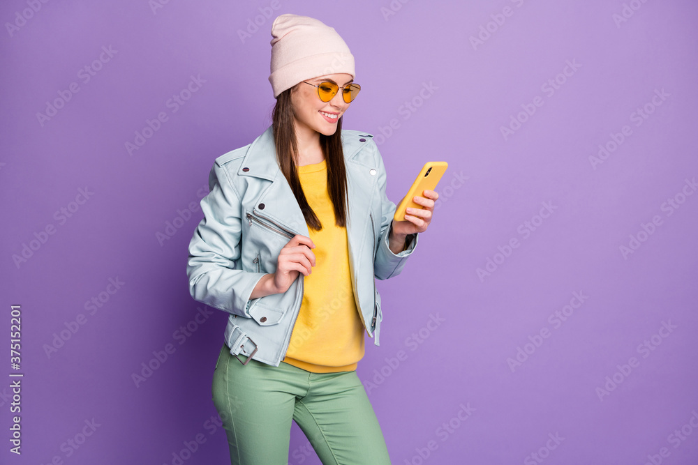 Profile photo of stylish pretty lady street look clothes hold telephone toothy smiling read news wear sun specs casual hat blue jacket pullover green pants isolated purple color background Profile photo of stylish pretty lady street look clothes hold telephone toothy smiling read news wear sun specs casual hat blue jacket pullover green pants isolated purple color background