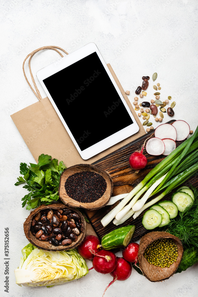 Tablet computer and shopping paper bag with healthy food. Top view. Tablet computer and shopping paper bag with healthy food. Top view.