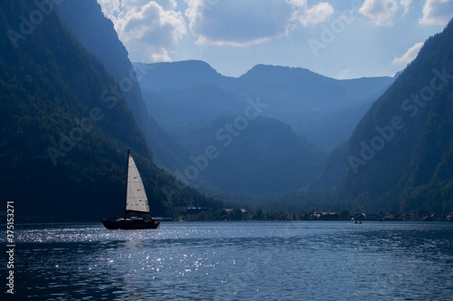 Beautiful scene of Sailing boat on Hallstatt lake and Alps in background 
