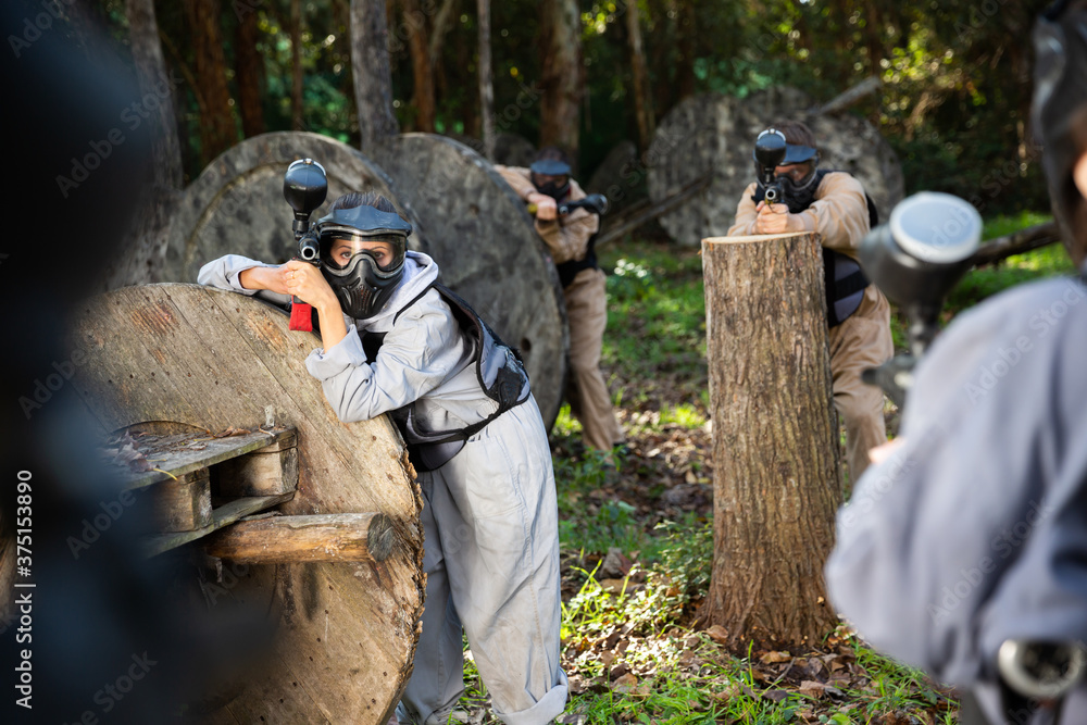 Fototapeta premium Two opposing teams of players shooting on paintball playing field outdoors