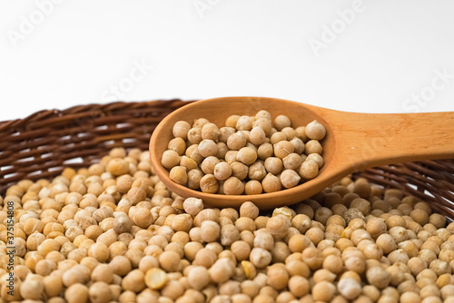 Chickpeas in a wooden spoon on a wicker plate. Raw chickpea.