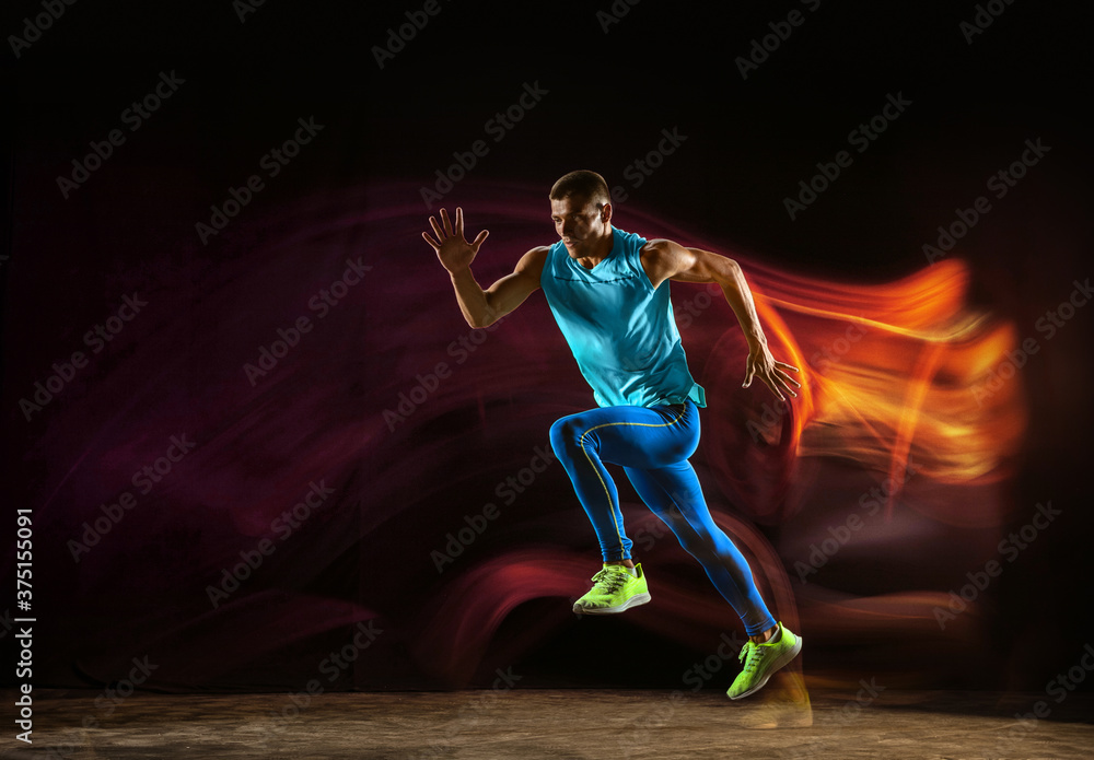 Professional male runner training isolated on black studio