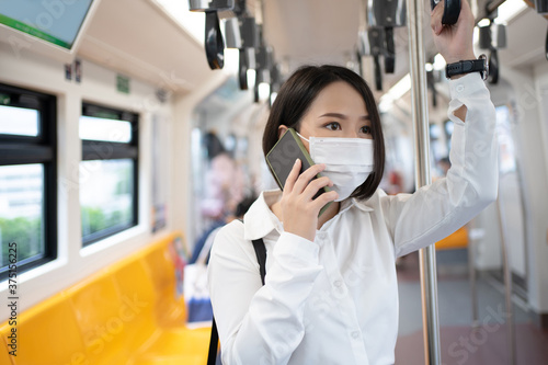 A young Asian businessman in a mask uses a phone in the subway while there is an outbreak of COVID-19 in the country. Concept of infection and outbreak.