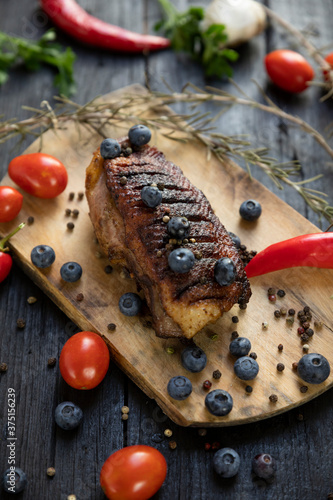 Goose breast Christmas roast with blueberries, tomatoes, red peppers and rosemary served on a wooden board photo