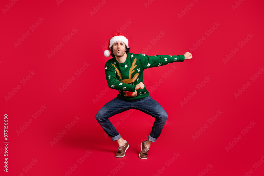 Full length body size view of his he nice attractive childish glad cheerful guy wearing Santa cap dancing having fun newyear festive fooling isolated bright vivid shine vibrant red color background
