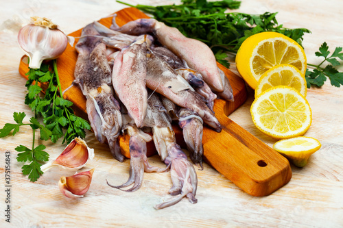 Raw squid with lemon, garlic and parsley on a wooden cutting board. High quality photo