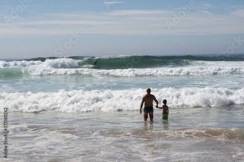 Father and son watching a person surfing