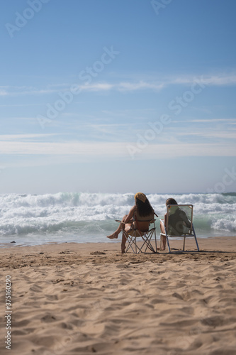 Two girls sitting on the shore reading a book