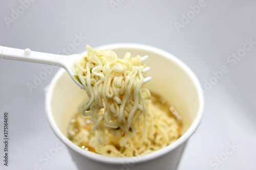 instant noodles, noodle soup in a cup, view from above. Instant noodles are sold in a precooked and dried noodle block, with flavoring powder and/or seasoning oil.