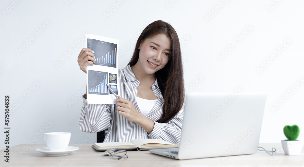 Young Asian woman works on paperwork in her own home online. Young Asian woman works on paperwork in her own home online.