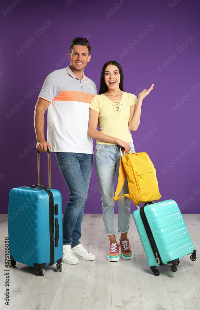 Happy couple with suitcases for summer trip near purple wall. Vacation travel Happy couple with suitcases for summer trip near purple wall. Vacation travel