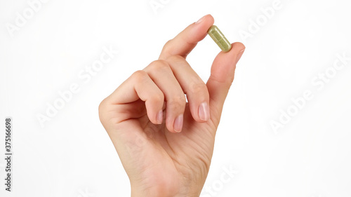 female hand holds in fingers capsule superfoods moringa or spirulina  photo