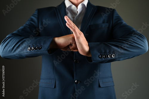 A man in a suit hits the palm with his fist. A man in a suit and a fist on a black background. Concept: construction in business.