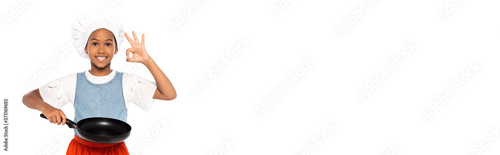 website header of african american kid in costume of chef showing ok sign while holding frying pan isolated on white website header of african american kid in costume of chef showing ok sign while holding frying pan isolated on white