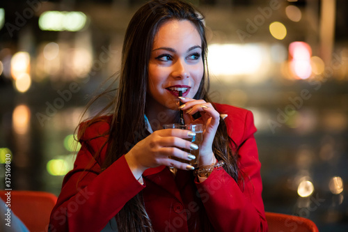 Young woman holding a drink at a night club outdoor photo