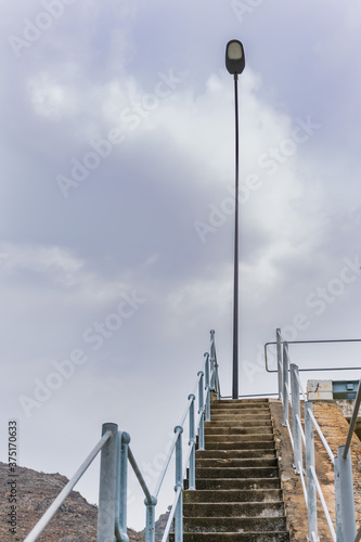 Steep stairs with railing and a lamppost on top