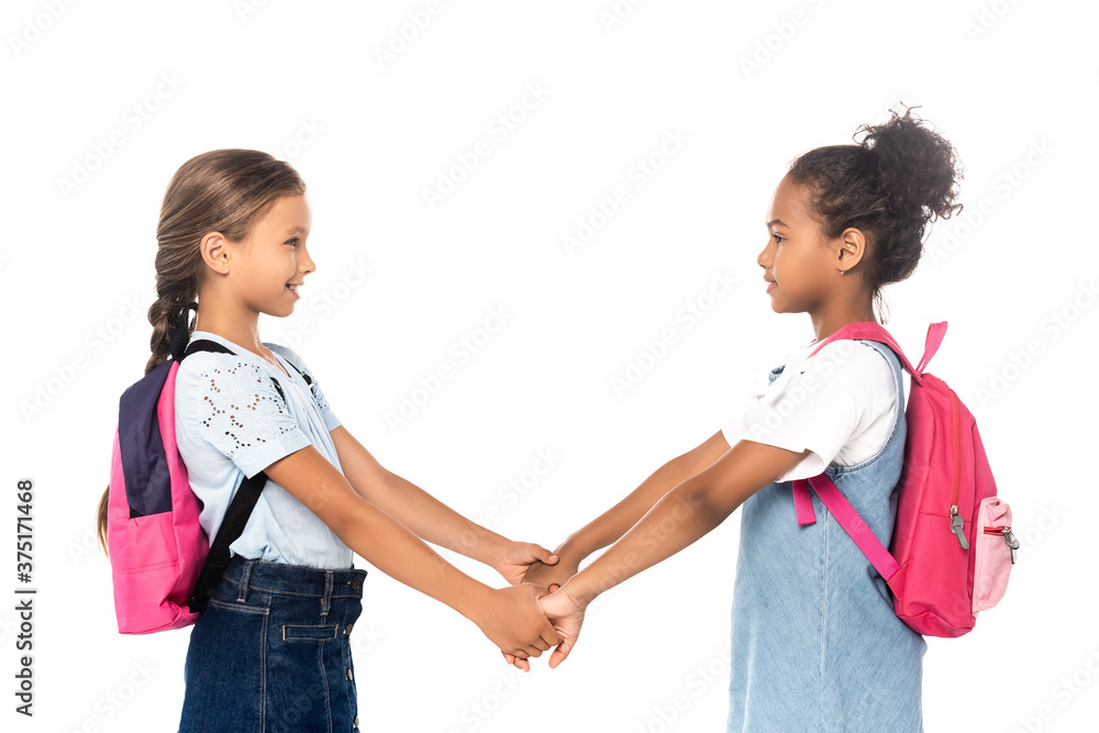 side view of multicultural schoolchildren holding hands isolated on white side view of multicultural schoolchildren holding hands isolated on white