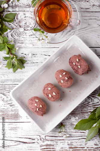 Kartoshka cake on the ceramic platter and a cup of tea. Russian potato-shaped dessert photo