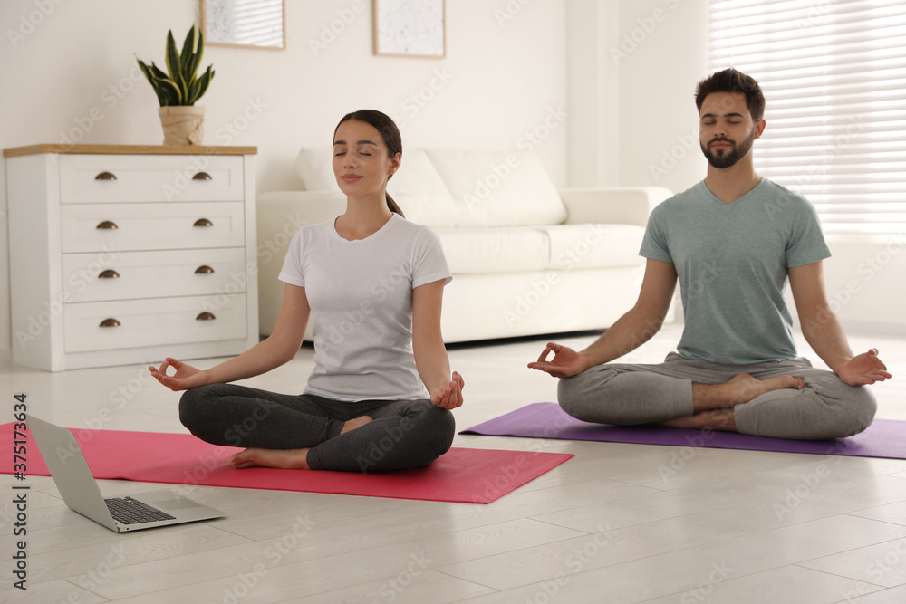 Couple practicing yoga while watching online class at home during coronavirus pandemic. Social distancing Couple practicing yoga while watching online class at home during coronavirus pandemic. Social distancing
