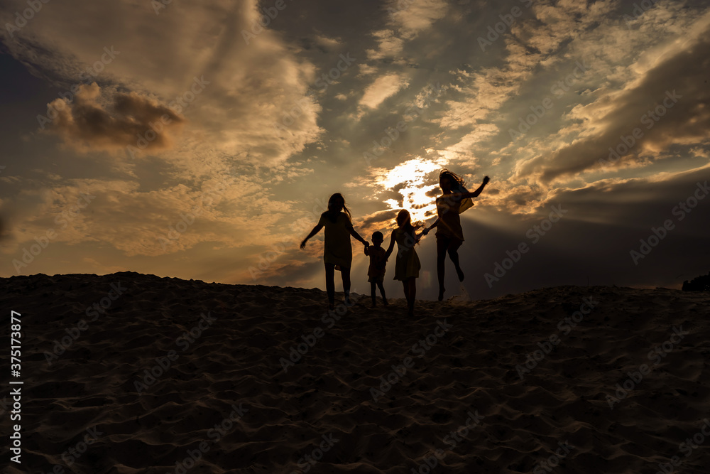 Obraz premium Sunset and family on the sand, silhouettes of people on the beach, success and family unity