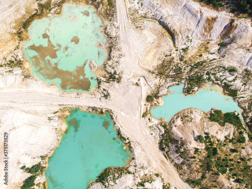 Drone view on a flooded kaolin quarry with turquoise water and white shore. Aerial survey of a kaolin pit flooded with water.
