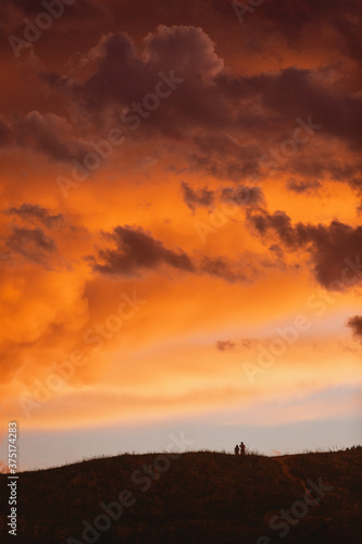 Couple of people on a hill at sunset