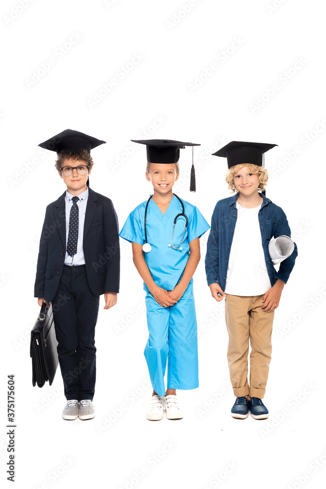 children in graduation caps dressed in costumes of different professions standing with stethoscope, blueprint and briefcase isolated on white children in graduation caps dressed in costumes of different professions standing with stethoscope, blueprint and briefcase isolated on white