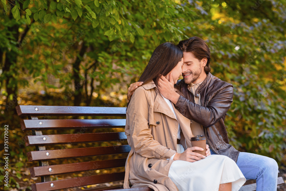 Beautiful romantic couple cuddling on bench at park Beautiful romantic couple cuddling on bench at park