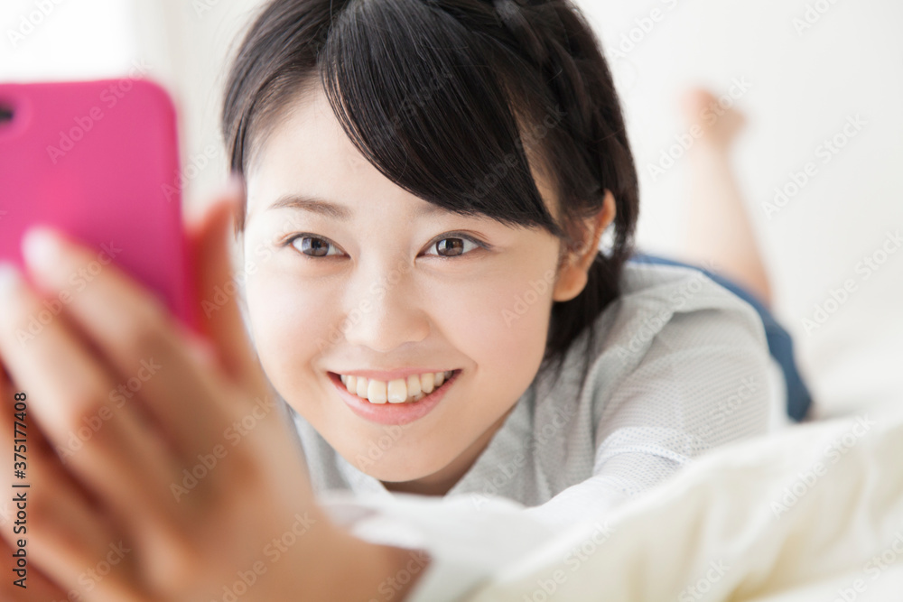 寝そべりながら携帯メールする女の子 寝そべりながら携帯メールする女の子