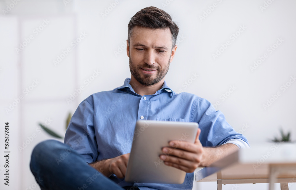 Portrait Of Handsome Young Man Using Digital Tablet During Break In Office Portrait Of Handsome Young Man Using Digital Tablet During Break In Office
