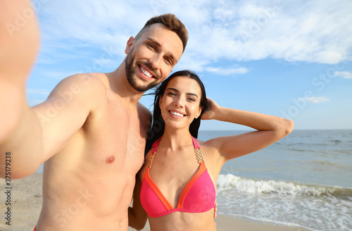 Happy young couple taking selfie on beach
