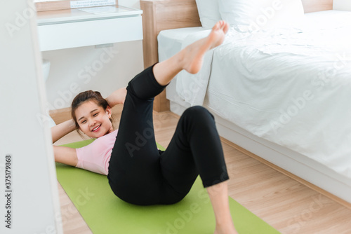Healthy women in sportswear clothes is doing a crunch exercise on yoga mat in bed room. Beautiful young woman exercises in home. 