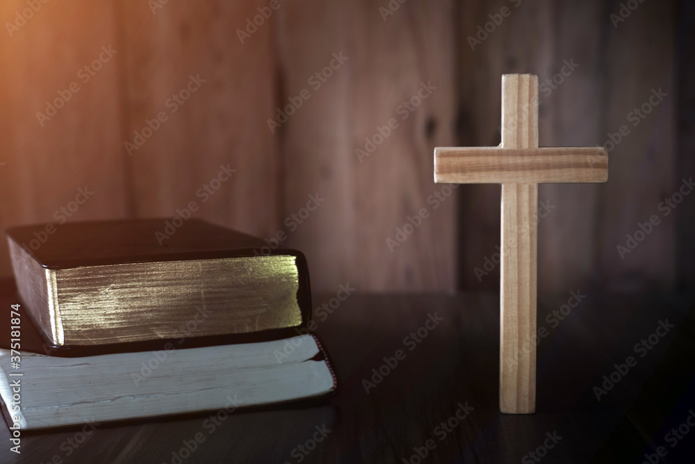The cross is placed near A pile of bible books While there are candles that illuminate the Christian religious concept, the crucifixion of faith and faith in God.
