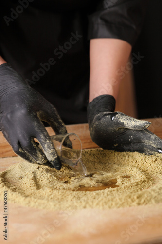 The cook kneads the mustard flour on wooden background