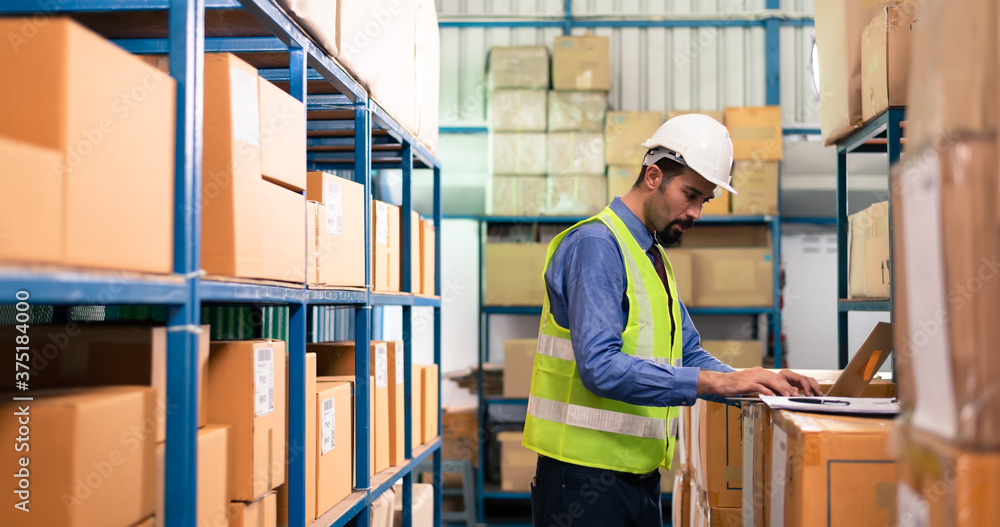 Male warehouse staff using computer working for stock management Male warehouse staff using computer working for stock management
