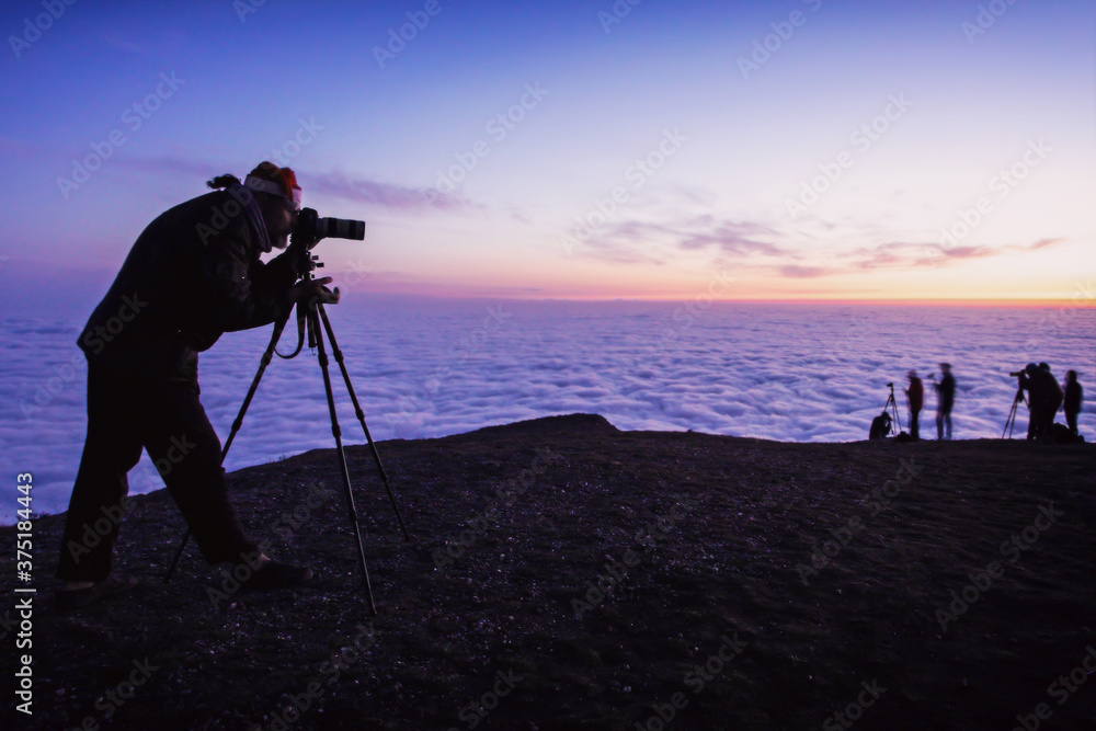 tourist in the mountains with thick clouds photographs the morning landscape of the rising sun on the horizon