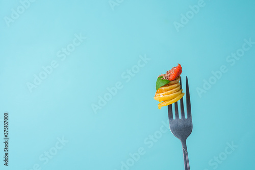 tiny pancakes on a fork with fresh strawberries, banana, chocolate, coconut chips and honey in a plate on a blue background. food trend 2020