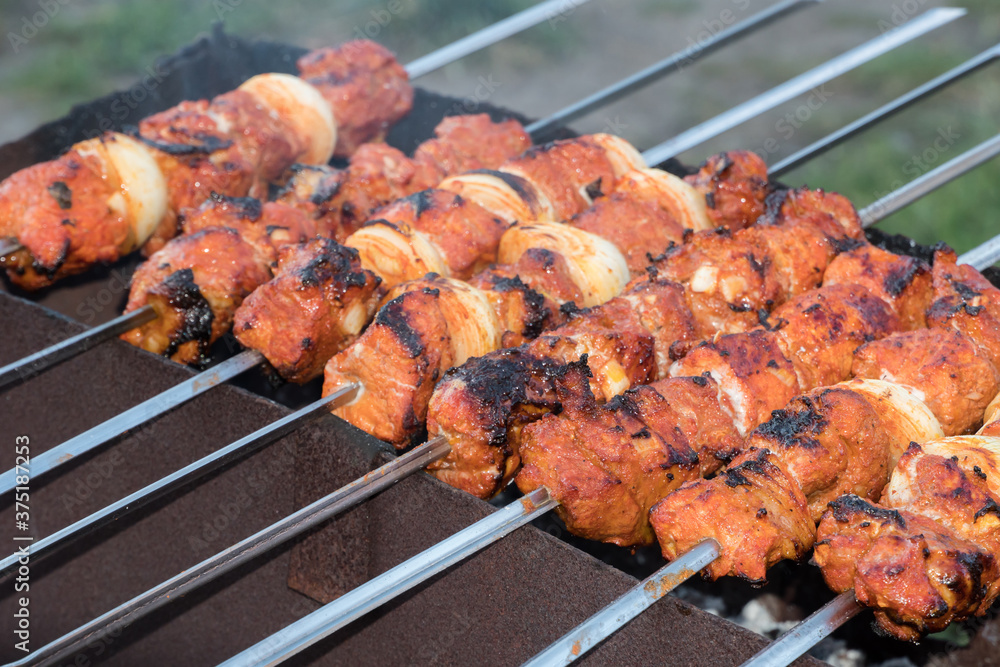Photo cooking fry shish kebab,BBQ, barbecue, shashlik or meat on coals. Cooking meat in the grill on skewers in nature in the summer on a picnic. Pork on the grill